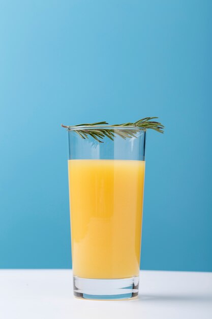 Dekoration mit einem Glas Orangensaft und Kräutern