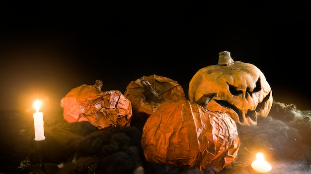 Dekorative Halloween-Kürbise, die unter brennenden Kerzen liegen