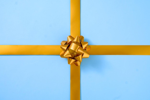 Dekoratives goldband mit einer schleife über blau in einem geschenkkonzept für besondere anlässe