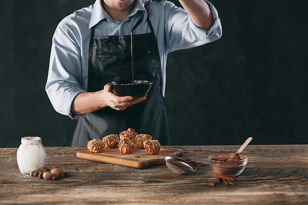 Dekorieren Sie köstliche hausgemachte Eclairs mit Schokolade und Erdnüssen