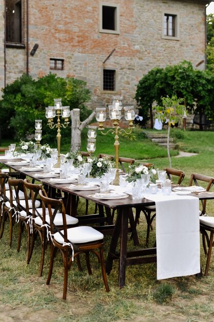 Dekorierter Hochzeitsfeier-Tisch mit Sitzplätzen für Gäste im Freien vor einem alten Gebäude aus Stein