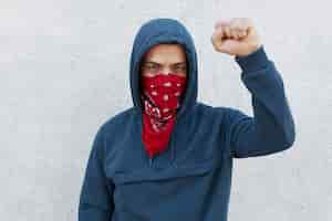 Kostenloses Foto demonstrant mit roter bandana-maske hebt die faust