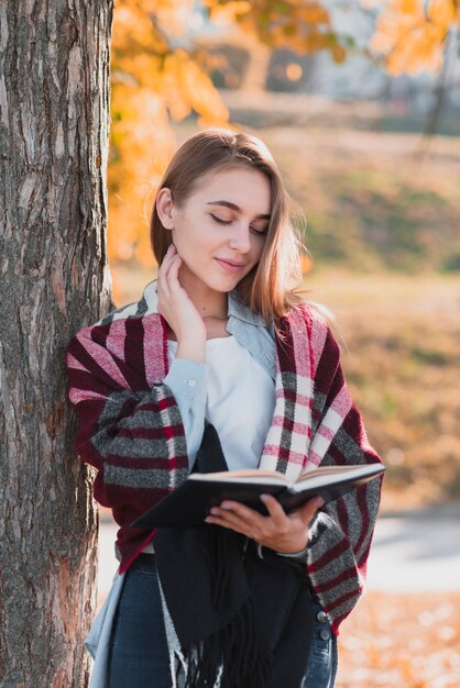 Denkende blonde Frau, die ein Notizbuch anhält