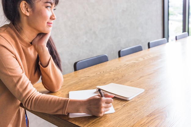 Denkende Dame mit Stift und Notizbüchern