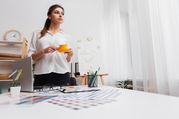 Kostenloses Foto denkende frau, die einen tasse kaffee hält