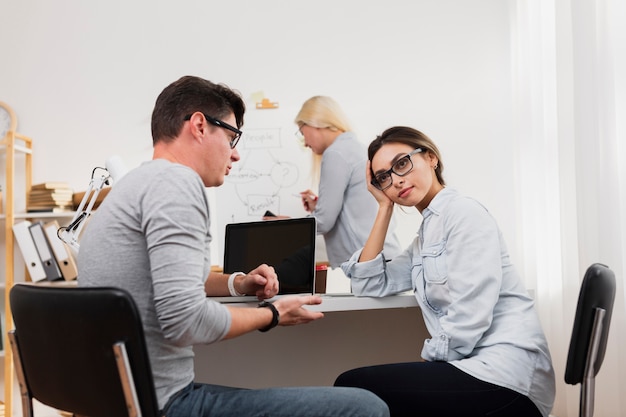 Denkende Frau, die mit Mann im Büro spricht