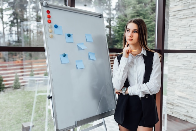 Kostenloses Foto denkende geschäftsfrau mit weißem schreibtisch für die planung eines neuen programms für ihre arbeiter.