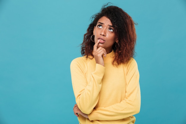 Denkende junge afrikanische Dame gekleidet in warmen Pullover