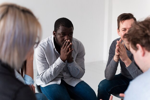 Denkender afroamerikanischer Mann, der Rehabilitationspatienten betrachtet