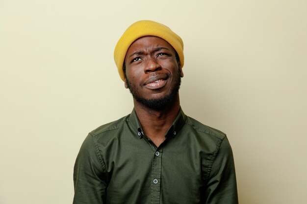 Denkender junger afrikanisch-amerikanischer Mann mit Hut und grünem Hemd auf weißem Hintergrund