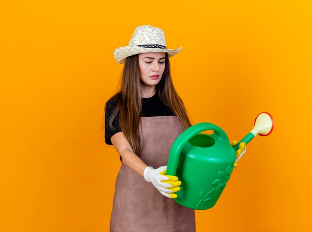 Denkendes schönes Gärtnermädchen, das Uniform und Gartenhut trägt