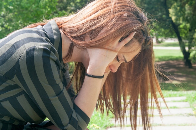 Kostenloses Foto deprimiertes mädchen, das auf bank im park sitzt