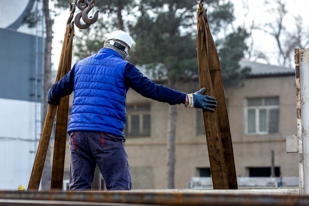 Der Arbeiter kontrolliert die Ladung am Kran