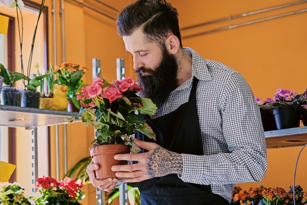 Der bärtige stilvolle Blumenverkäufer hält rosa Rosen in einem Marktladen.