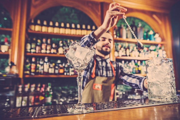 Der barmann macht einen alkoholischen cocktail an der theke in der bar