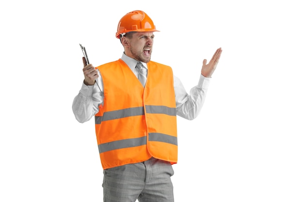 Der Baumeister in einer Bauweste und einem orangefarbenen Helm steht auf weißem Studio