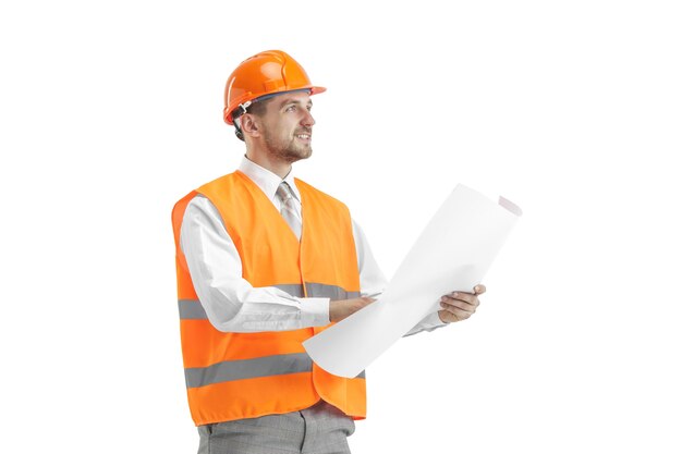 Der Baumeister in einer Bauweste und einem orangefarbenen Helm steht auf weißer Wand. Sicherheitsspezialist, Ingenieur, Industrie, Architektur, Manager, Beruf, Geschäftsmann, Jobkonzept