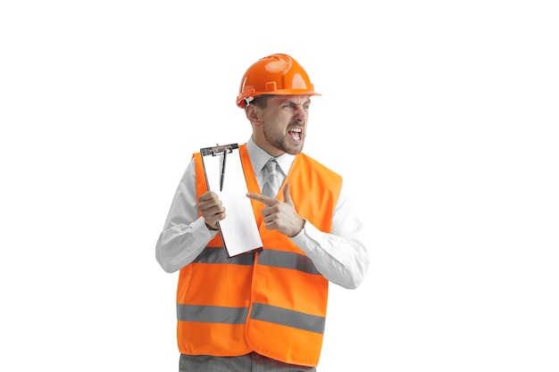 Der Baumeister in einer Bauweste und einem orangefarbenen Helm steht auf weißer Wand. Sicherheitsspezialist, Ingenieur, Industrie, Architektur, Manager, Beruf, Geschäftsmann, Jobkonzept