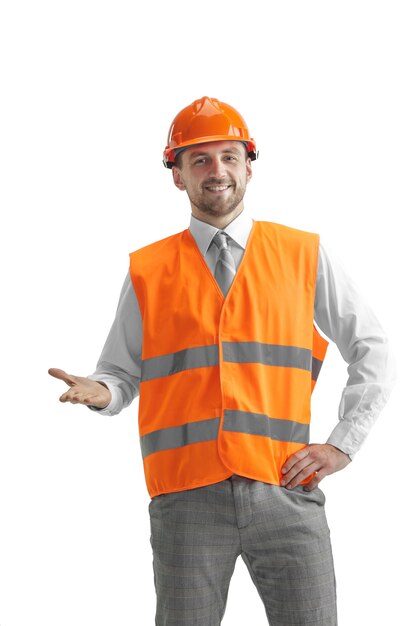 Der Baumeister in einer Bauweste und einem orangefarbenen Helm steht auf weißer Wand. Sicherheitsspezialist, Ingenieur, Industrie, Architektur, Manager, Beruf, Geschäftsmann, Jobkonzept