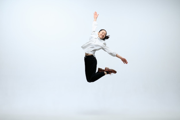 Kostenloses Foto der beginn des neuen lebens. glückliche frau, die im büro arbeitet, springend und tanzend in der freizeitkleidung oder im anzug lokalisiert auf weißem studiohintergrund. business, start-up, funktionierendes open-space-konzept.