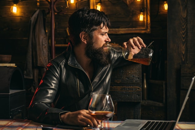 Der biker kommt an die bar. frustrierter mann mit bart trinkt aus einer flasche whisky. probleme in beziehungen. alkoholismus, alkoholsucht und menschenkonzept.