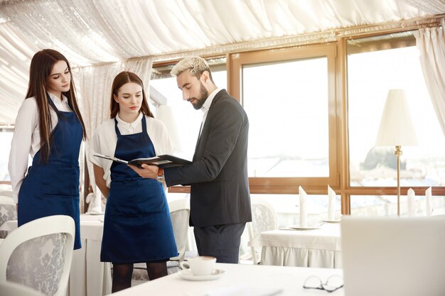 Der Direktor eines Restaurants gibt den Kellnerinnen Arbeitsanweisungen