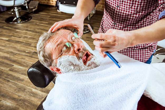 Der emotionale ältere Mann, der Friseur im Friseurladen besucht