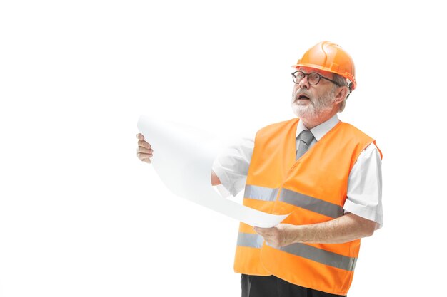 Der Erbauer in einer Bauweste und in einem orangefarbenen Helm, der auf weißem Studiohintergrund steht. Sicherheitsfachkraft, Ingenieur, Industrie, Architektur, Manager, Beruf, Kaufmann, Berufskonzept