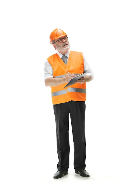 Der Erbauer in einer Bauweste und in einem orangefarbenen Helm, der auf weißem Studiohintergrund steht. Sicherheitsfachkraft, Ingenieur, Industrie, Architektur, Manager, Beruf, Kaufmann, Berufskonzept