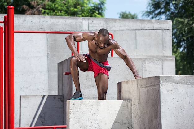 Der fitte Athlet macht Übungen. Afro oder Afroamerikanermann im Freien an der Stadt. Sportübungen hochziehen.