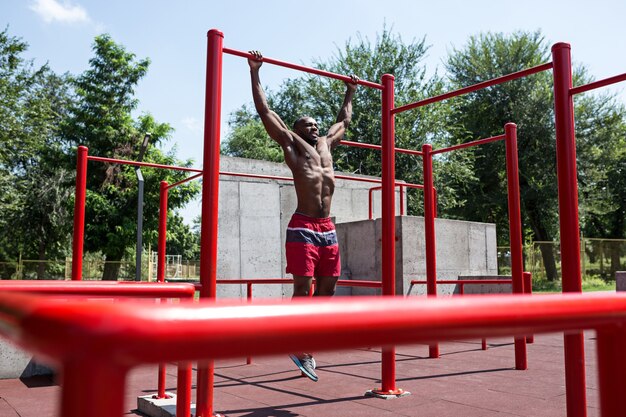 Der fitte Athlet macht Übungen im Stadion. Afro oder Afroamerikanermann im Freien an der Stadt. Sportübungen hochziehen. Fitness-, Gesundheits-, Lifestyle-Konzept