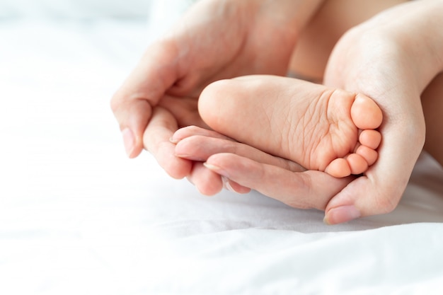 Der Fuß des Babys liegt in den Händen der Mutter.