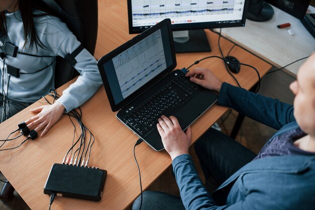 Der Geschäftskonkurrent hat den Vorsitz. Mädchen geht Lügendetektor im Büro vorbei. Fragen stellen. Polygraphentest