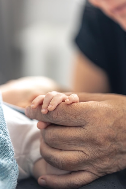 Der Griff eines Neugeborenen in den Händen einer Großmutter in Großaufnahme