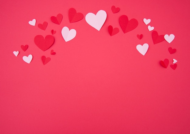 Der Hintergrund des St.-Valentinsgrußes mit den rosa und roten Papierherzen