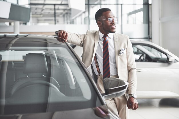 Der junge attraktive schwarze Geschäftsmann kauft ein neues Auto, Träume werden wahr.