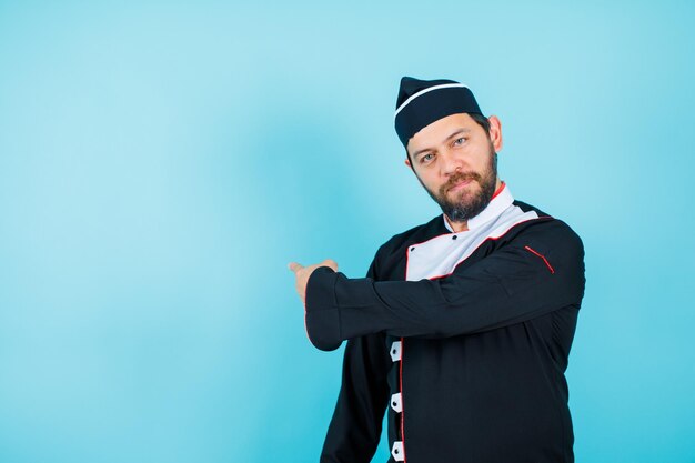 Der junge Koch zeigt sich mit dem Zeigefinger auf blauem Hintergrund