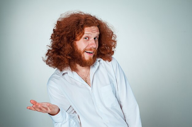 Der junge lächelnde Mann mit den langen roten Haaren, die Kamera betrachten