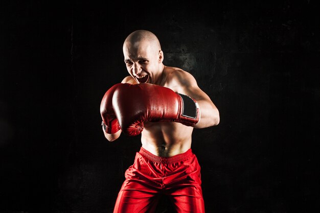 Der junge männliche Athlet tritt auf einem schwarzen Kickboxen