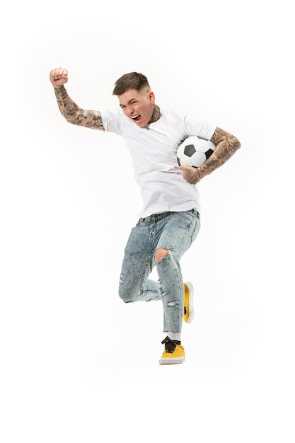 Der junge Mann als Fußballspieler tritt den Ball im Studio