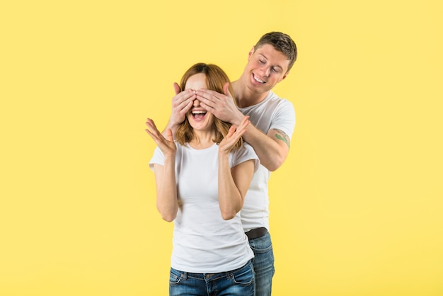 Der junge Mann, der ihre Freundinnen bedeckt, mustert mit zwei Händen, die auf gelbem Hintergrund zucken