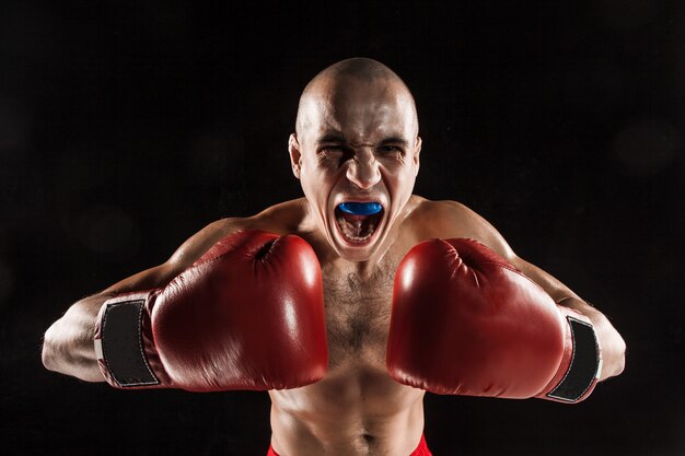 Der junge Mann Kickboxen auf Schwarz mit Kapa im Mund