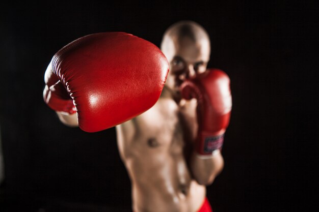 Der junge Mann Kickboxen auf Schwarz