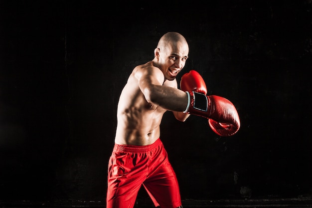 Kostenloses Foto der junge mann kickboxen auf schwarz