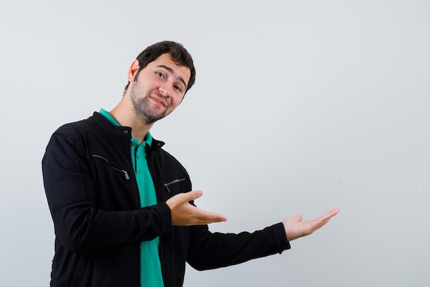 Der junge Mann zeigt mit den Händen auf weißem Hintergrund nach rechts