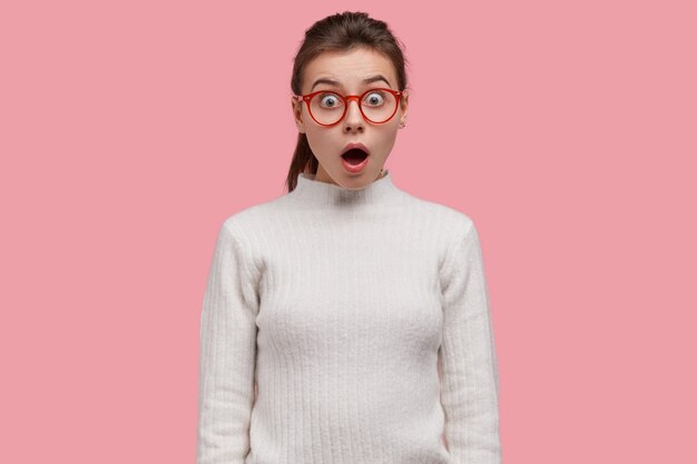 Der junge Teenager ist verblüfft über die schockierende Szene, trägt eine Brille und ein lässiges Outfit, ist sprachlos und verärgert