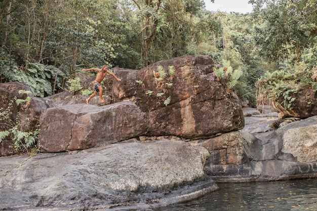 Der Kerl springt von einem Stein ins Wasser