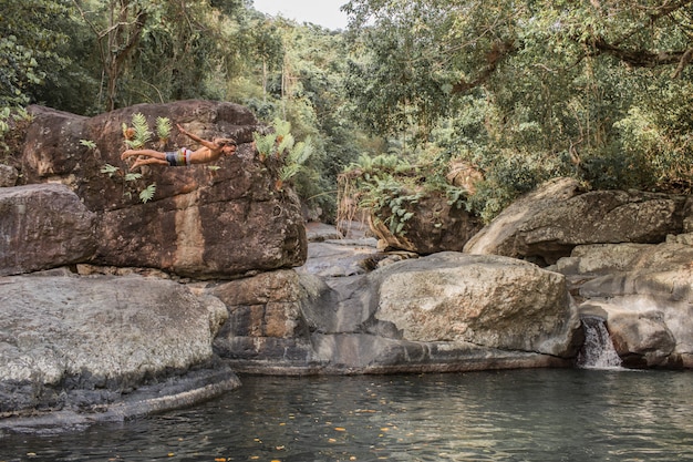 Der Kerl springt von einem Stein ins Wasser