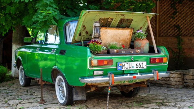 Der Kofferraum eines grünen Oldtimers ist mit Blumen geschmückt