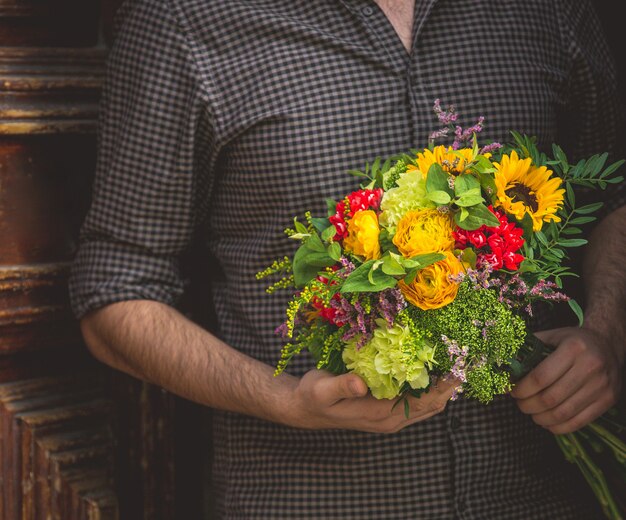 Der Mann, der einen Blumenstrauß der Herbstsonne hält, spornte Blumen an